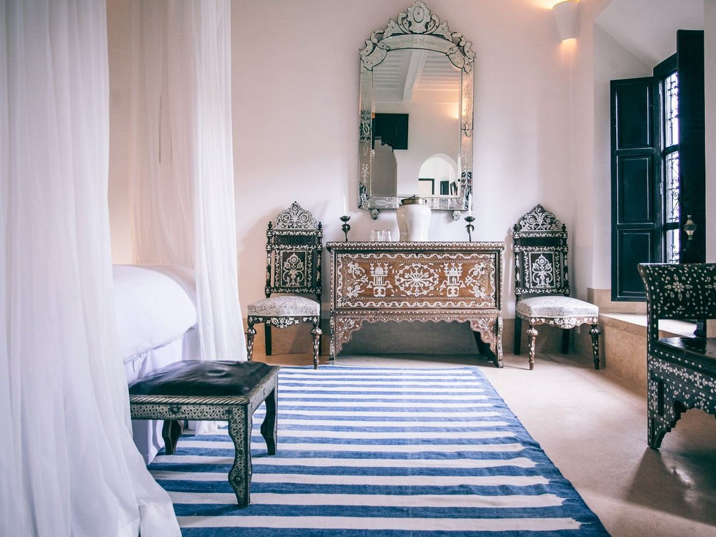 Chambre marocaine lumineuse, lit blanc et tapis à rayures