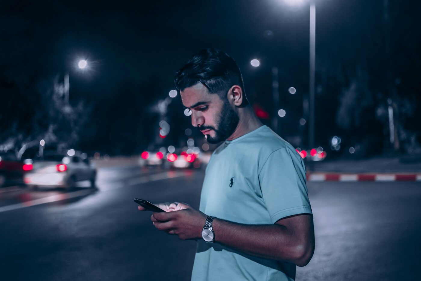Homme qui consulte son smartphone le soir dans la rue